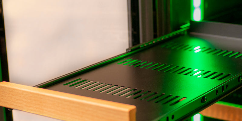 Emerald green light reflects off of the metal of a fridge shelf